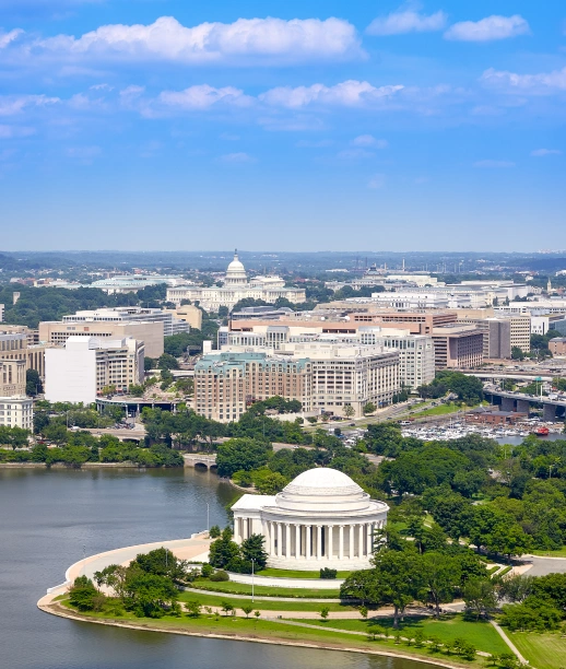 Panoramic Washington DC cityscape showing Jefferson Memorial waterfront and Capitol building under blue sky