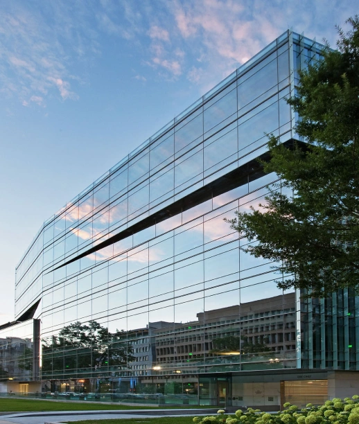 Sleek commercial building with reflective windows surrounded by landscaping and evening sky