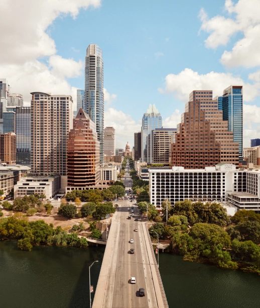 Aerial view of downtown city skyline with bridge spanning river and tree lined waterfront