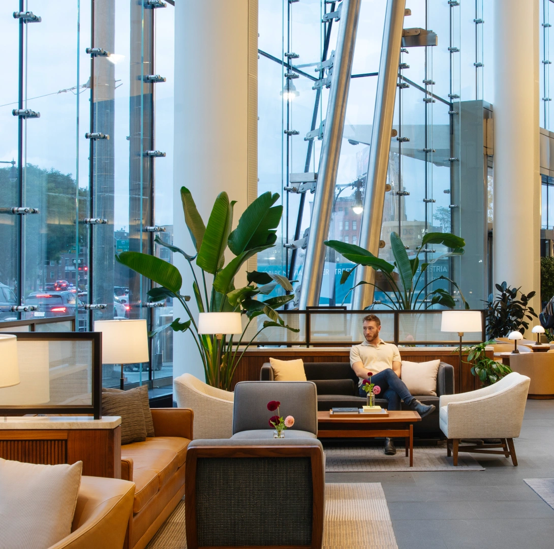 Corporate atrium lounge featuring biophilic design natural light modern furniture and urban street views