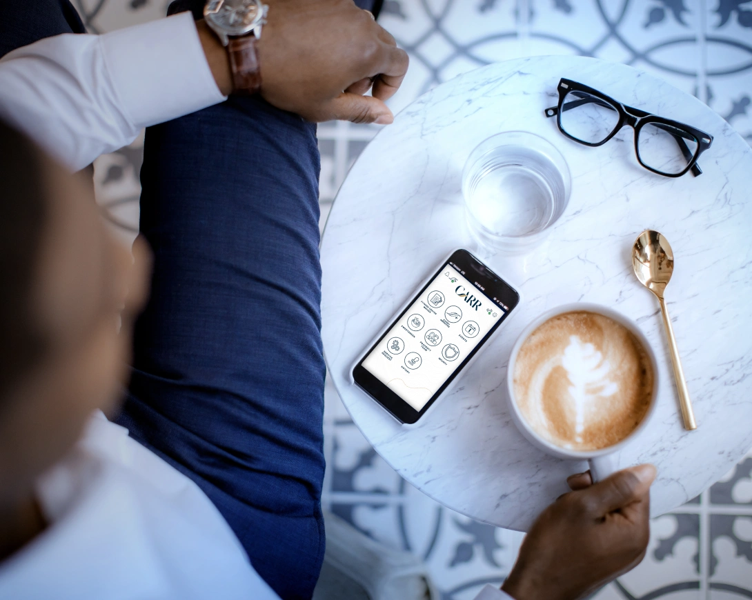 Top down lifestyle image of business professional using mobile app beside coffee cup