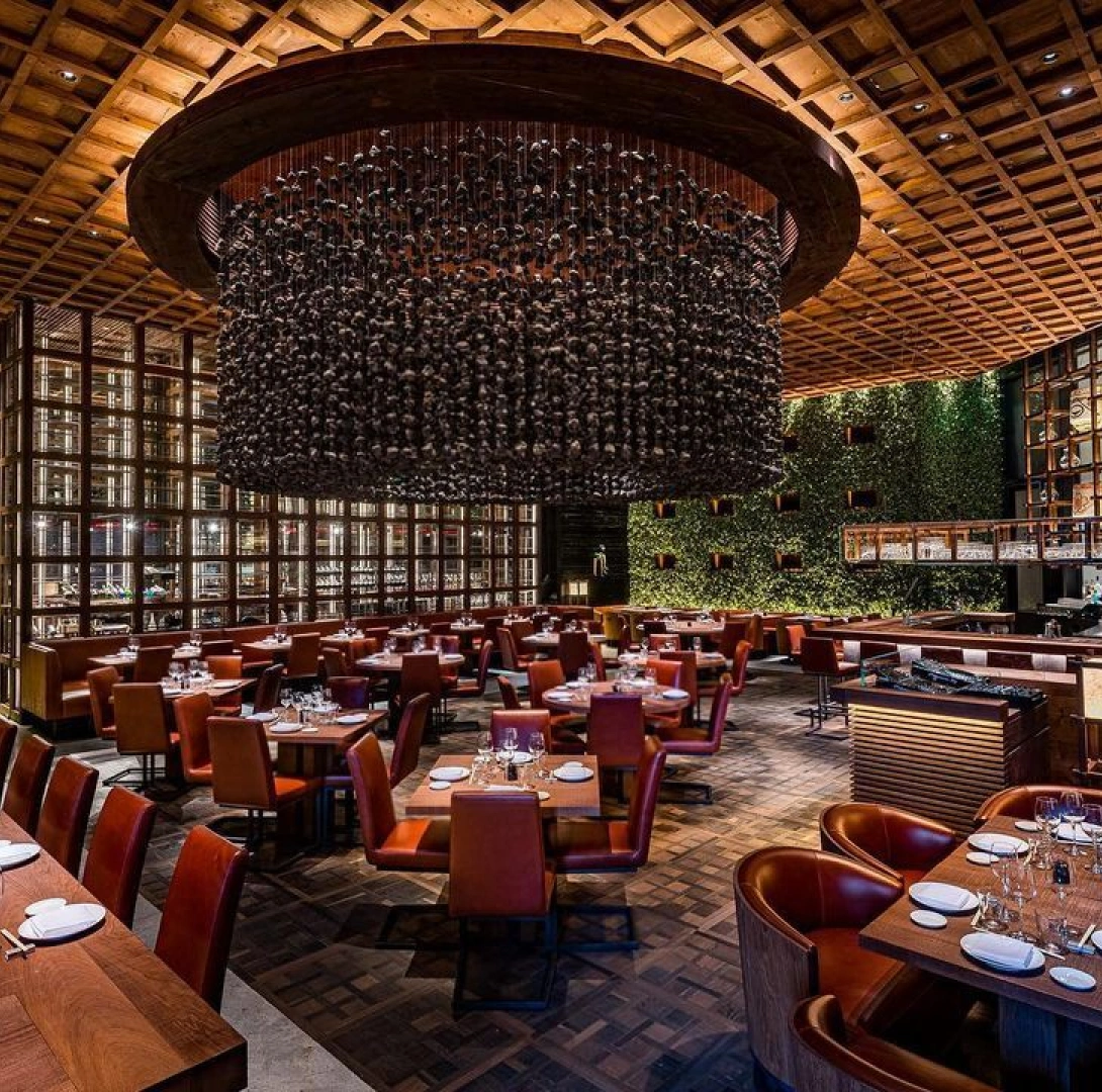 High end dining room with sculptural chandelier, warm wood textures, and modern restaurant ambiance
