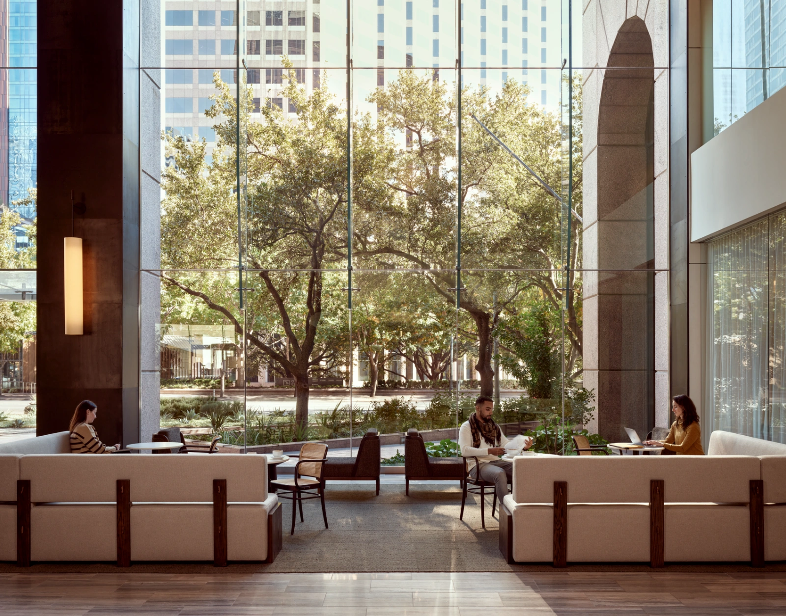 Modern office lobby lounge with professionals working beside floor to ceiling glass windows