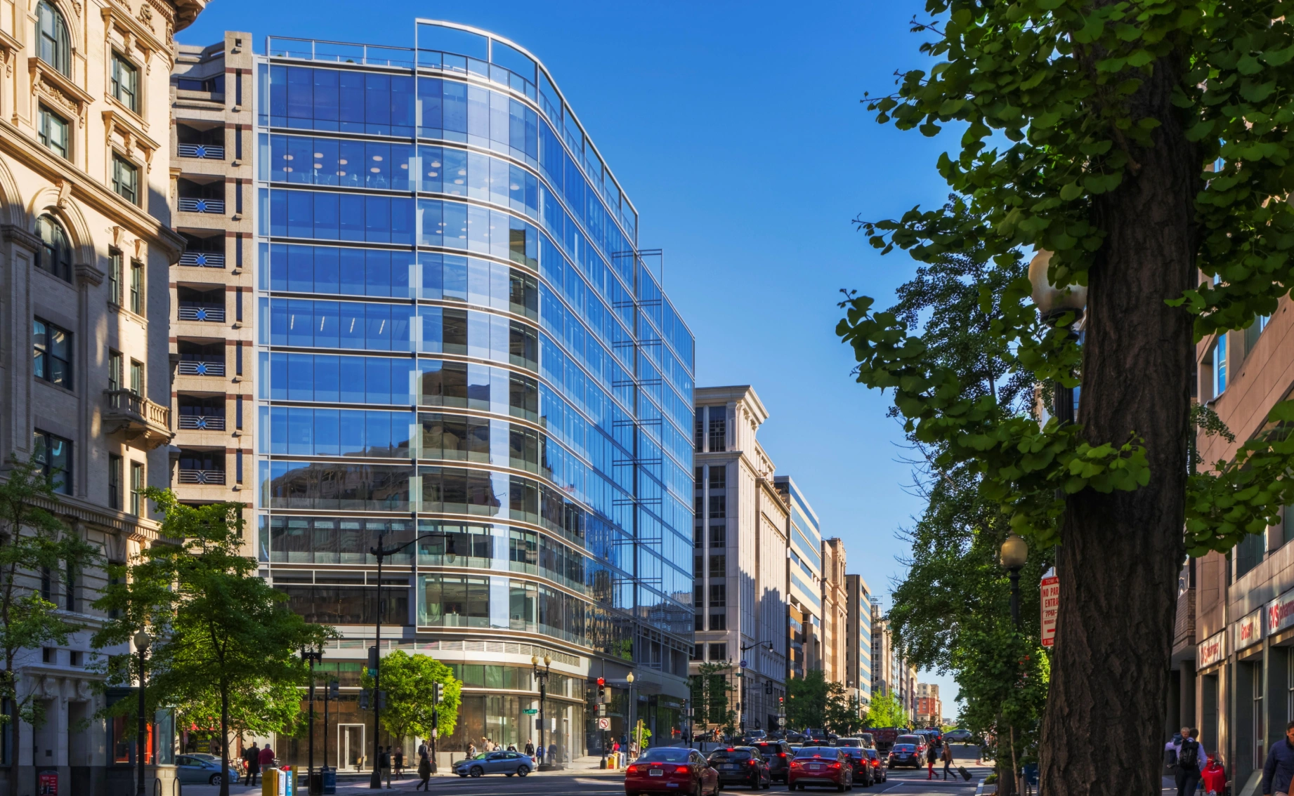 Downtown commercial office building with curved glass design street traffic and surrounding historic buildings