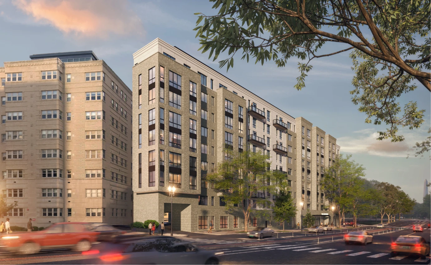 Modern urban residential building featuring brick facade, large windows, and busy intersection at sunset