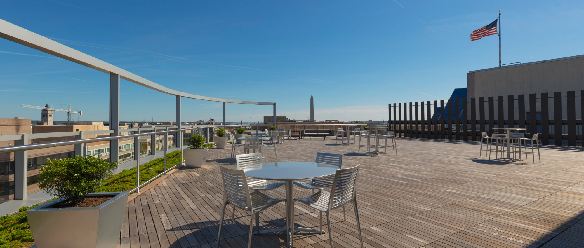 Urban rooftop amenity space with patio furniture panoramic city views and blue sky