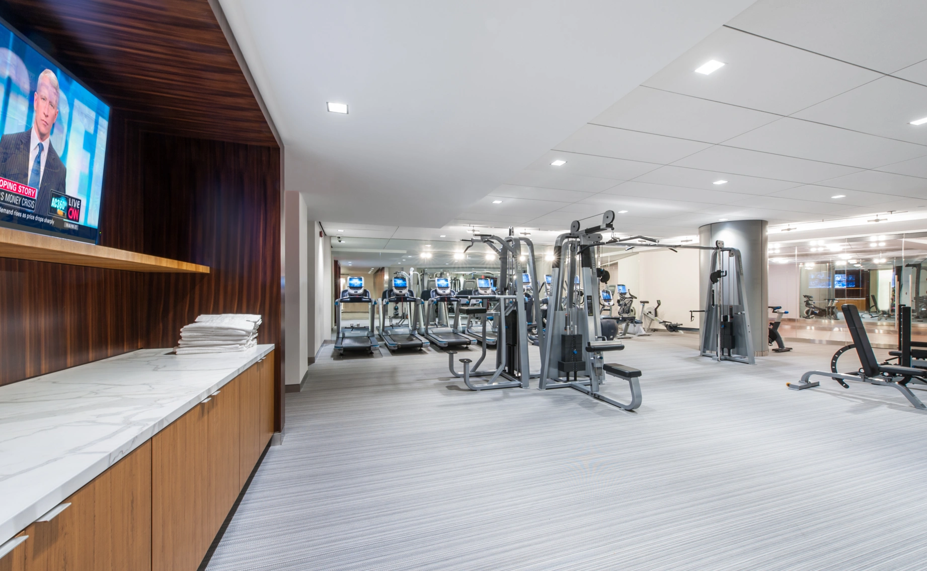 Luxury apartment gym featuring cardio equipment strength machines clean flooring and bright lighting