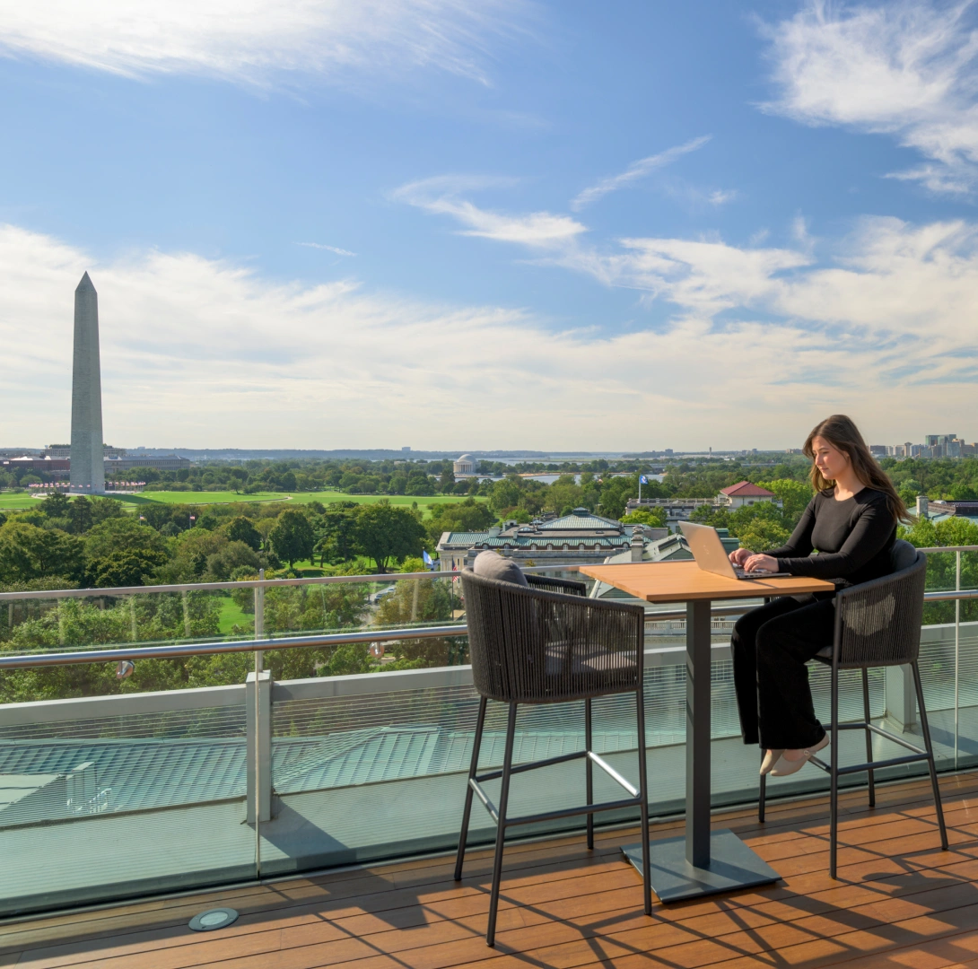 Scenic rooftop deck featuring table seating, laptop workspace, and Washington Monument in distance